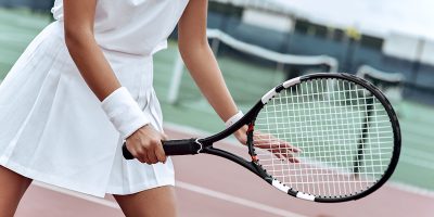 Close up of a young woman ready to hit a tennis ball, serving a ball during game.