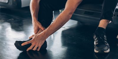 Close up of young fit and active female athlete suffering from ankle tendon ligament twisted and sprained from sports activity