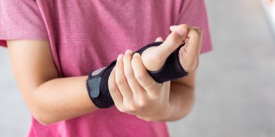 Young woman holding her wrist pain because using computer long time. De Quervain's tenosynovitis, Intersection Symptom, Carpal Tunnel Syndrome or Office syndrome.Disease and healthcare concept